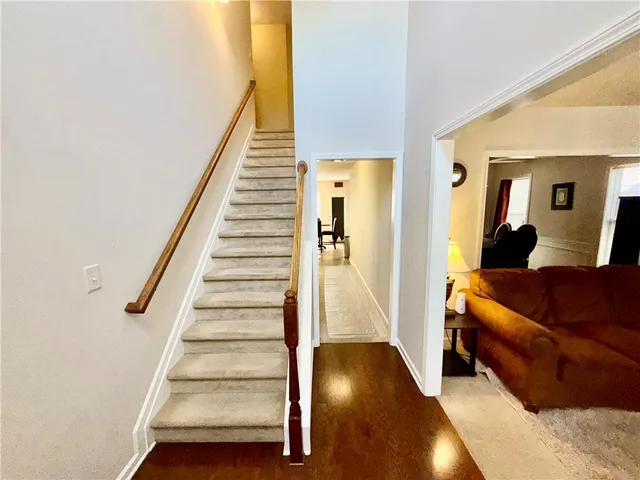 a view of a hallway to a livingroom with wooden floor and furniture