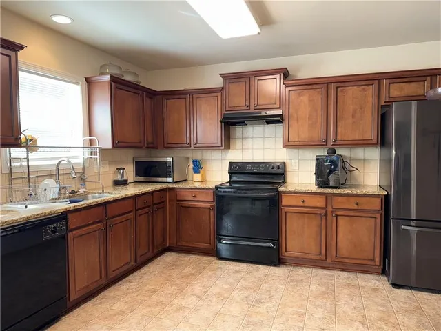 a kitchen with stainless steel appliances granite countertop a stove top oven a sink dishwasher and a refrigerator