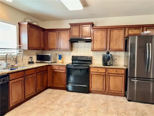 a kitchen with stainless steel appliances granite countertop a refrigerator stove top oven and sink