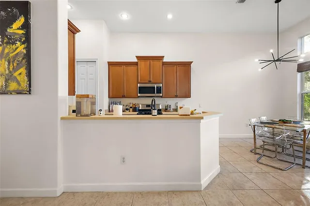 a room with stainless steel appliances kitchen island granite countertop a refrigerator a stove a sink with a dining table and chair with wooden floor
