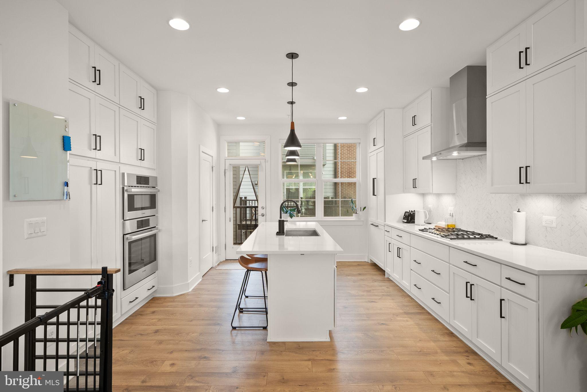 11258 Faraday Park Drive Reston, VA 20190 - Photo 9 of 44 a large kitchen with stainless steel appliances kitchen island granite countertop a large stove a refrigerator a sink and white cabinets with wooden floor