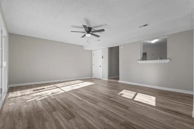 a view of empty room with wooden floor and fan