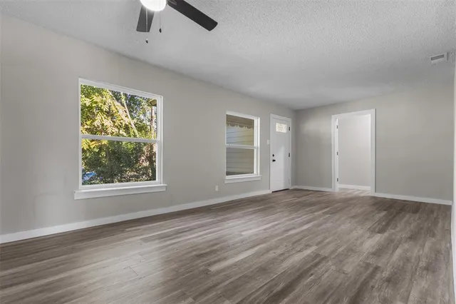 a view of an empty room with window and wooden floor