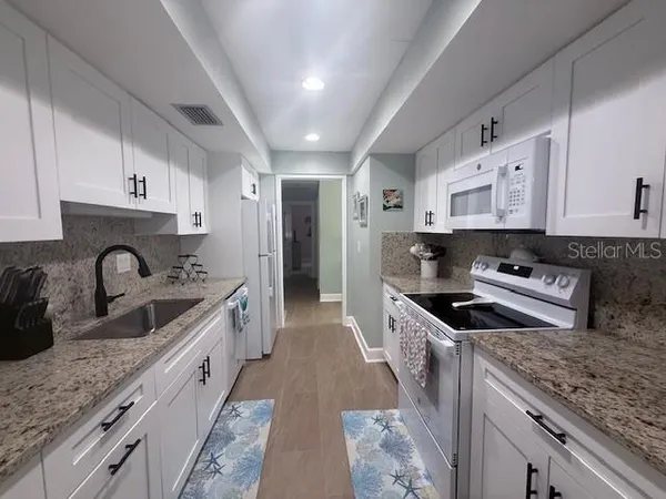 a kitchen with stainless steel appliances granite countertop a sink stove and refrigerator