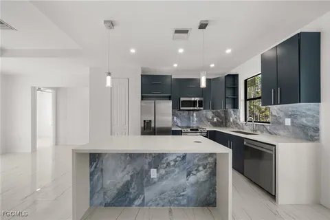 a kitchen with stainless steel appliances granite countertop a refrigerator and a stove top oven