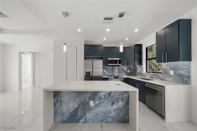 a large kitchen with stainless steel appliances granite countertop a sink a stove and a refrigerator