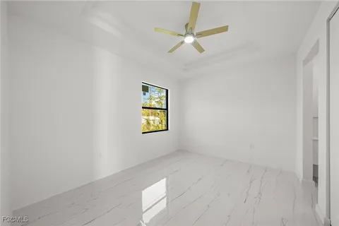 an empty room with windows and fan
