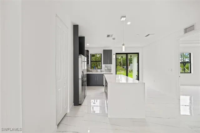 a large kitchen with kitchen island a large counter top and stainless steel appliances