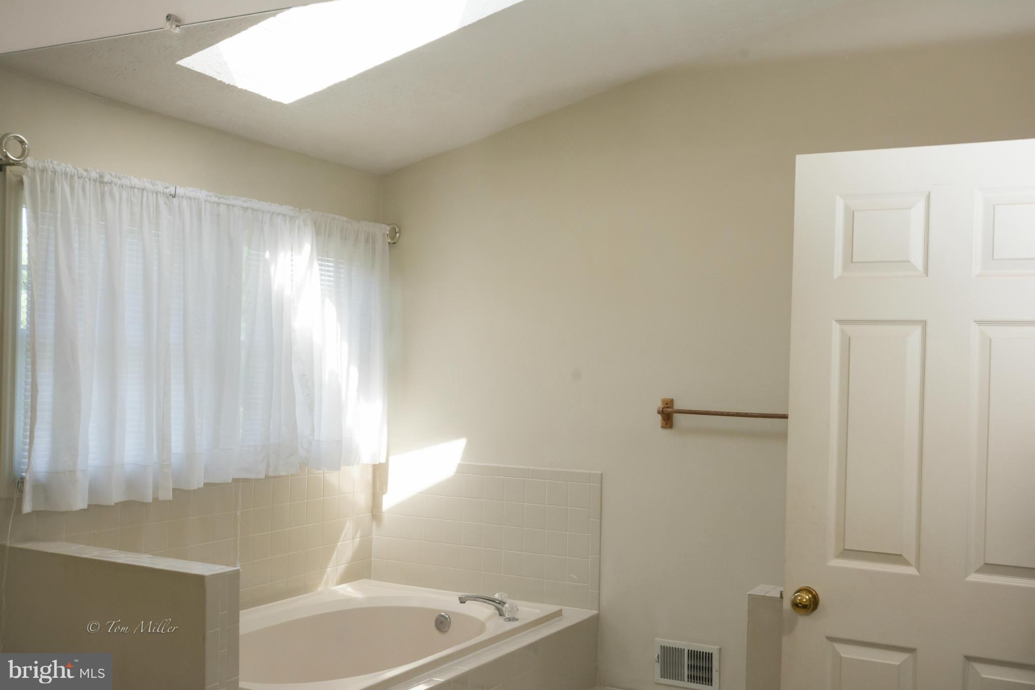 910 Metfield Road Baltimore, MD 21286 - Photo 12 of 22 a bathroom with a bathtub a shower and a window