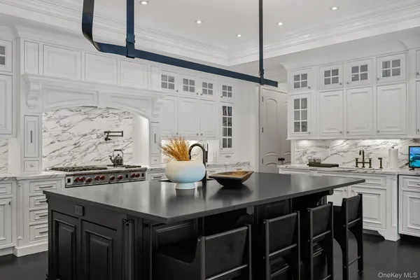 a kitchen with stainless steel appliances kitchen island a stove a sink and white cabinets