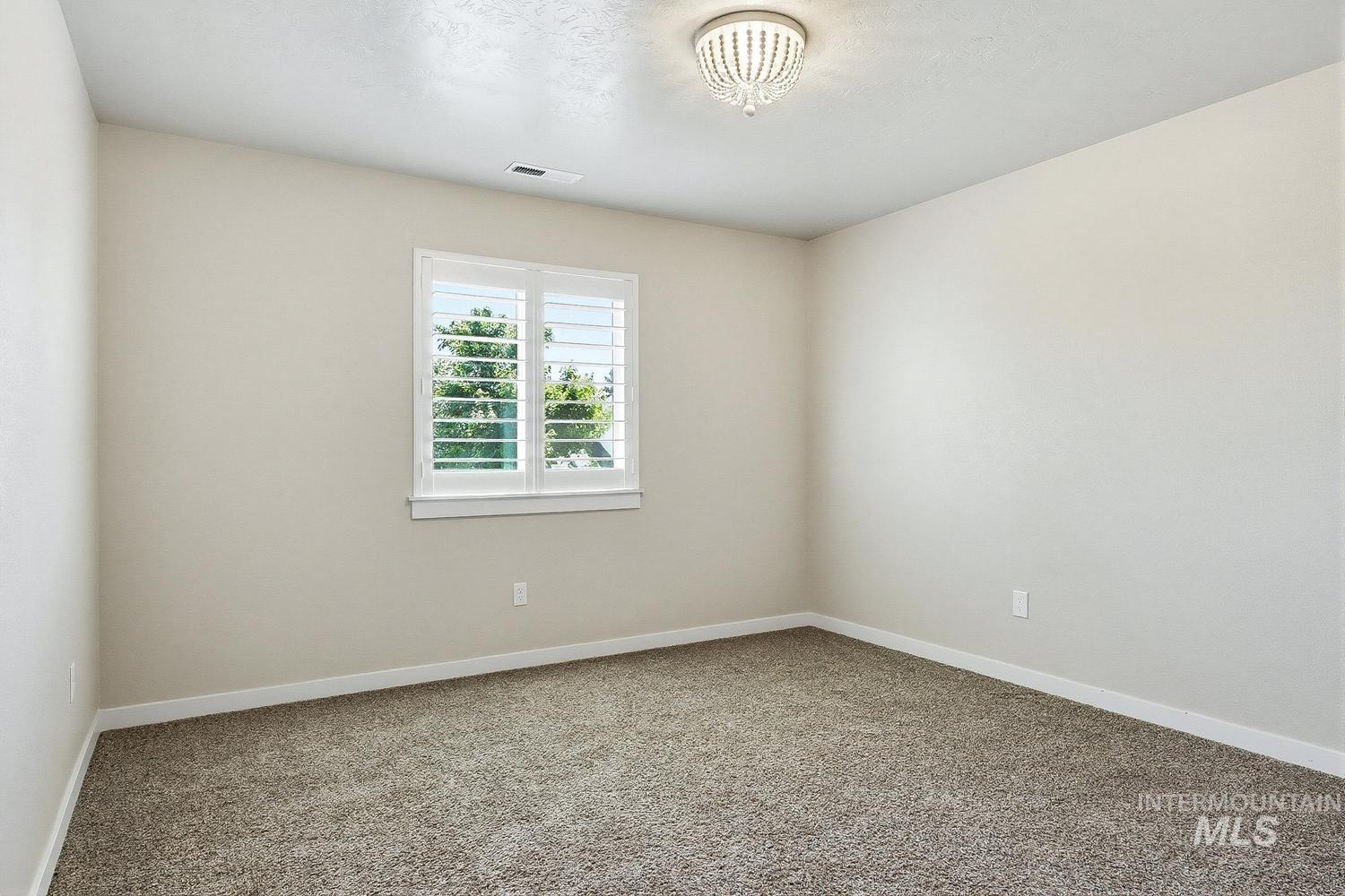 846 North Hidden View Way Star, ID 83669 - Photo 42 of 49 Spacious room featuring neutral paint, textured carpet, and a window with plantation shutters
