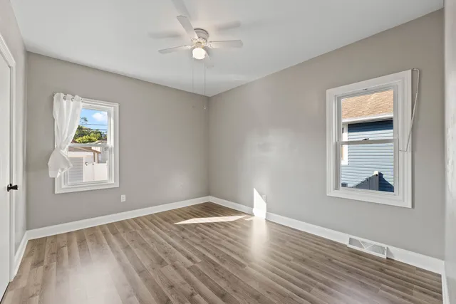 a view of an empty room with a window and wooden floor