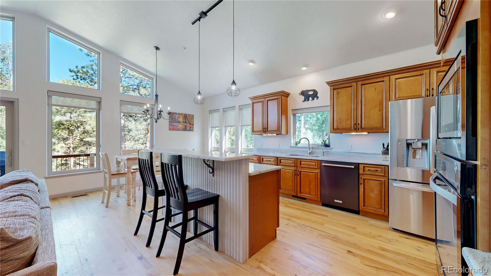 230 Mohawk Trail Pine, CO 80470 - Photo 8 of 39 a open kitchen with stainless steel appliances granite countertop a refrigerator a stove a sink a dining table and chairs with wooden floor