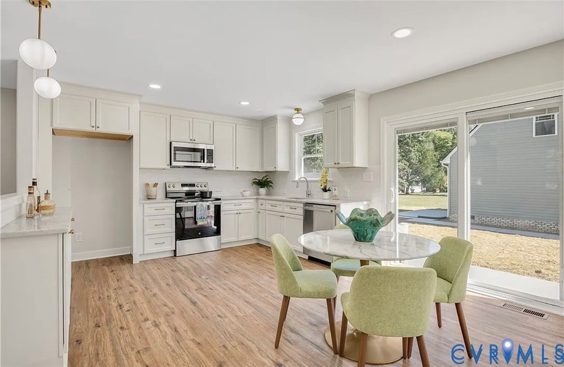 a kitchen with stainless steel appliances granite countertop a stove a refrigerator a kitchen island a table and chairs