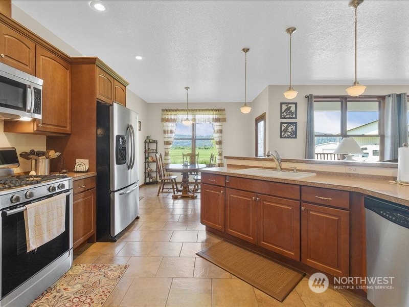 285 West Birnie Slough Road Cathlamet, WA 98612 - Photo 6 of 40 a kitchen with stainless steel appliances granite countertop a stove a sink a refrigerator and chairs