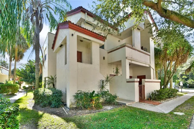 a view of a white house with a big yard and potted plants