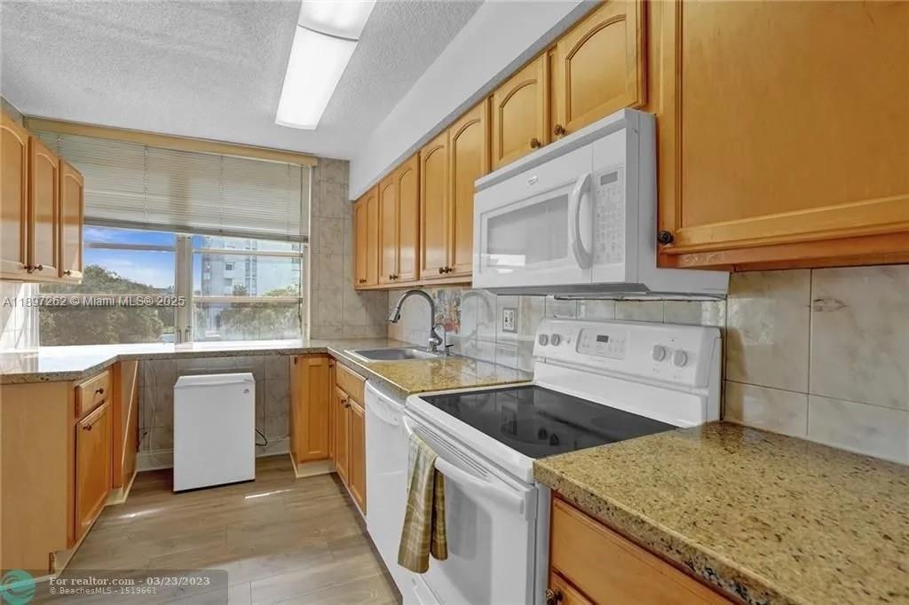 7051 Environ Boulevard, Unit 337 Lauderhill, FL 33319 - Photo 3 of 15 a kitchen with stainless steel appliances granite countertop a sink and dishwasher a stove top oven with wooden floor
