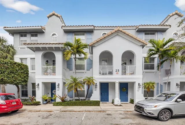a view of a white house with large windows and a table and chairs