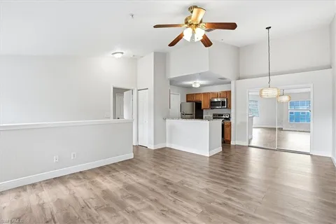 a view of a kitchen and an empty room with wooden floor