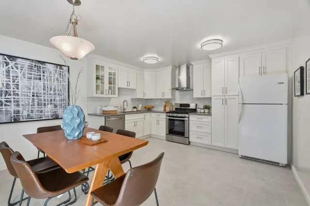 a kitchen with stainless steel appliances granite countertop a stove a refrigerator a kitchen island a table and chairs