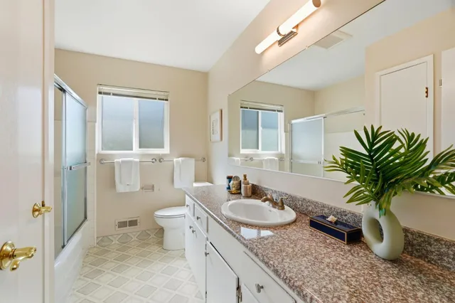 a bathroom with a granite countertop sink a toilet and a mirror