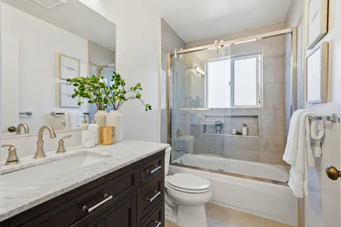 a bathroom with a granite countertop sink a toilet and shower
