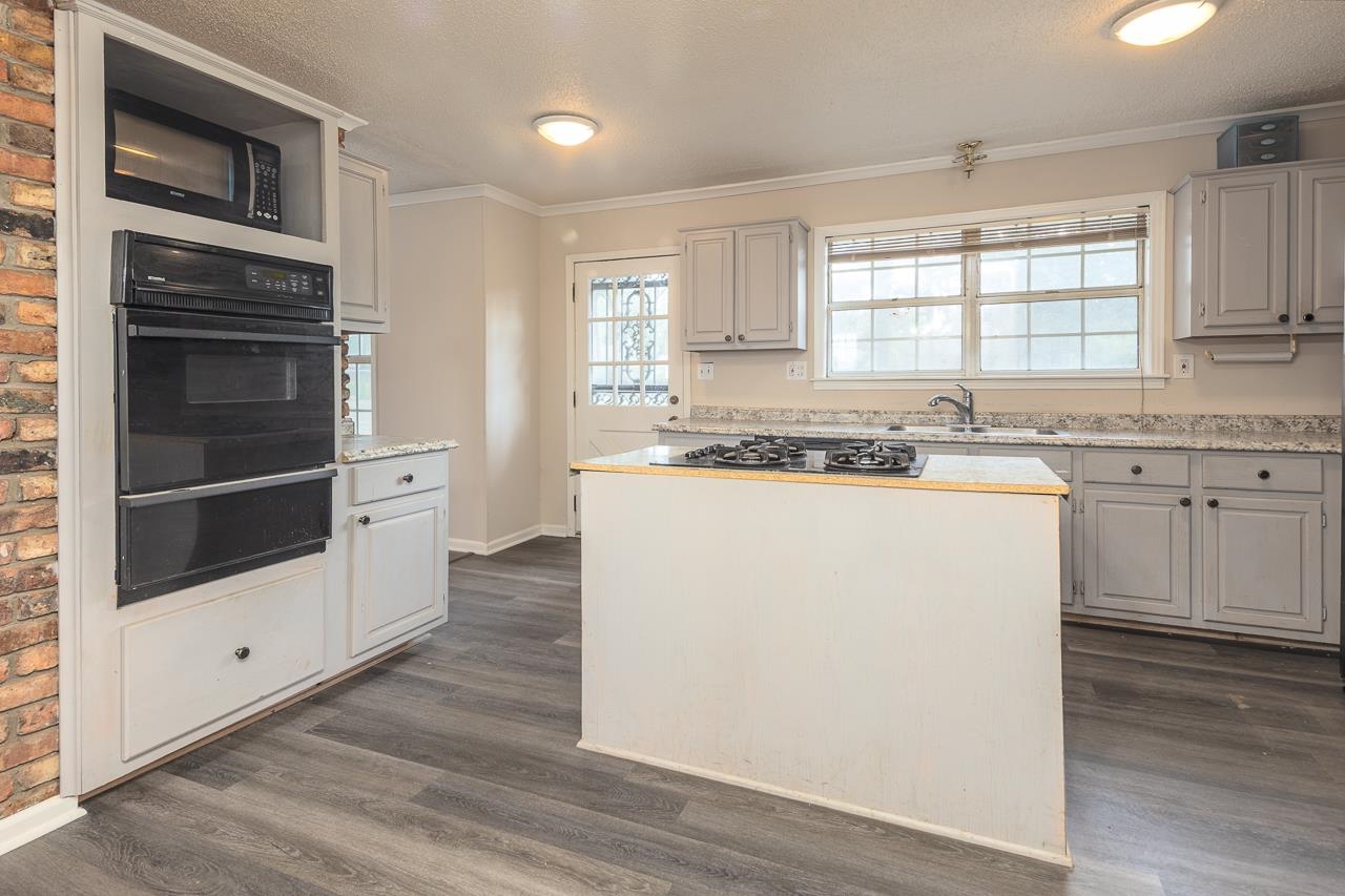 2718 Kate Bond Road Memphis, TN 38133 - Photo 9 of 39 Kitchen with black appliances, healthy amount of natural light, a warming drawer, ornamental molding, and a center island