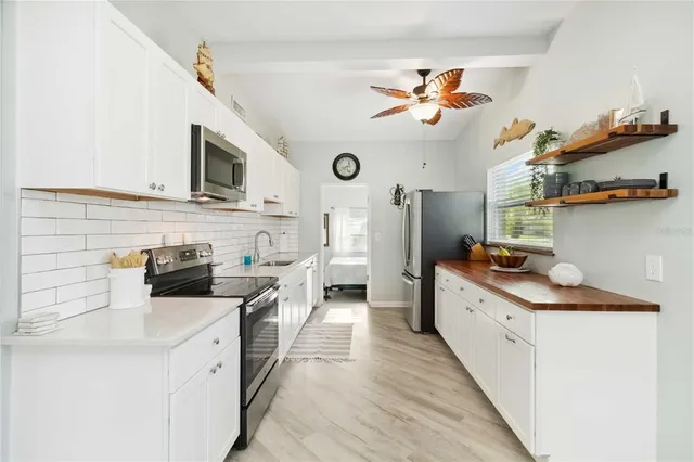 a kitchen with kitchen island granite countertop a sink a counter top space stainless steel appliances and a chandelier