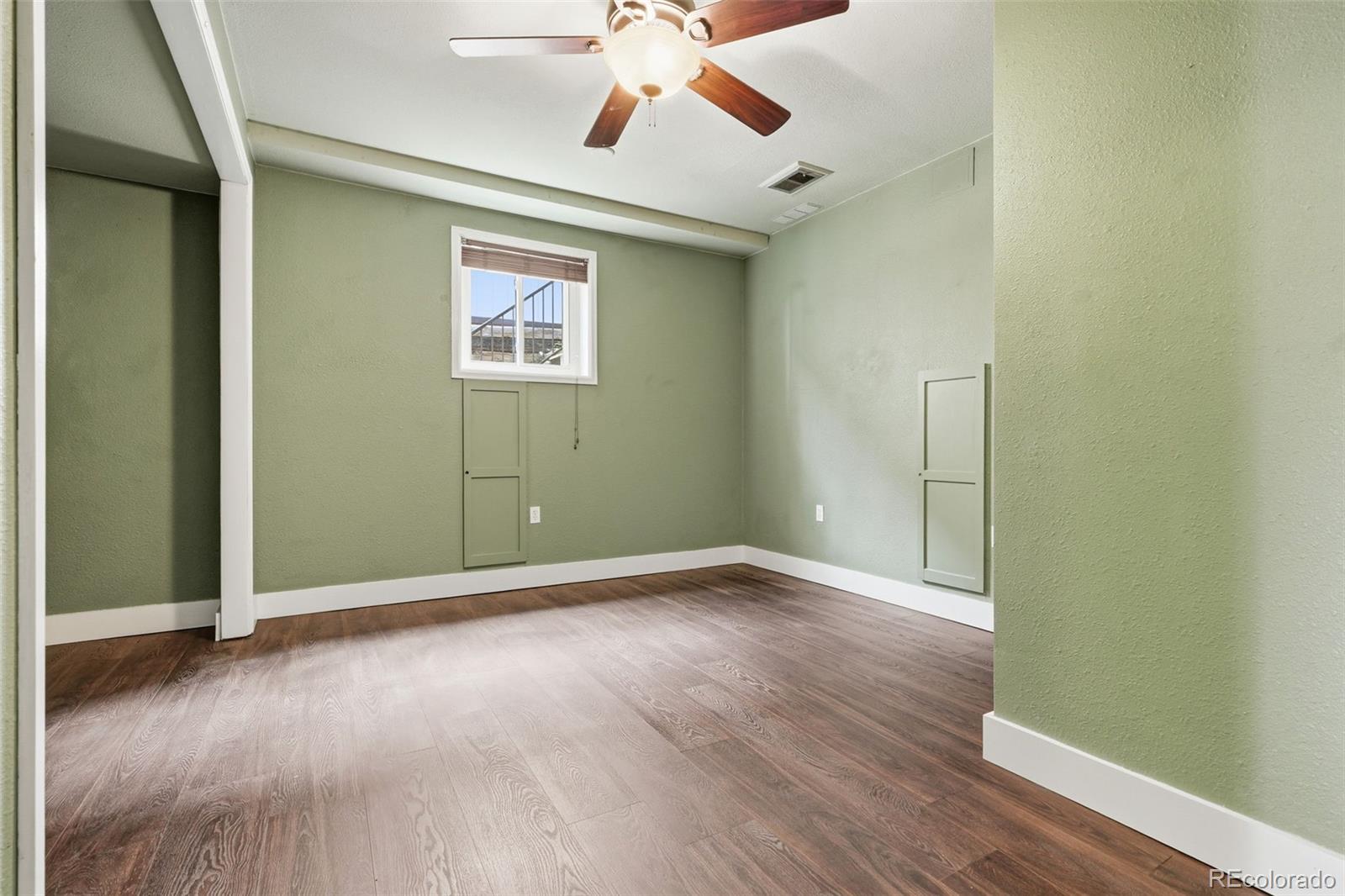 15743 Wedge Way Morrison, CO 80465 - Photo 35 of 48 an empty room with wooden floor chandelier fan and windows