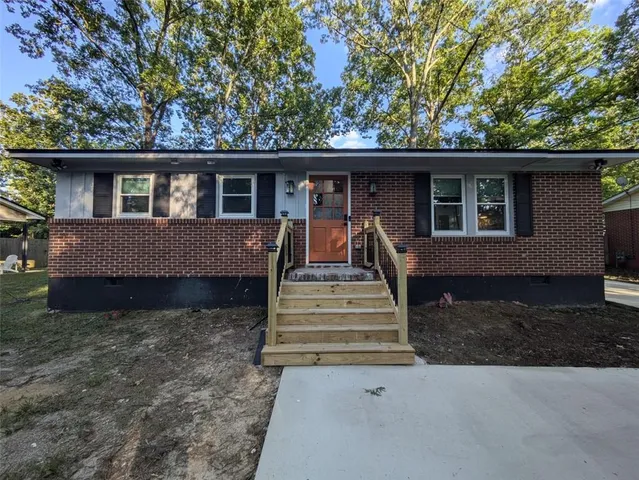 a front view of a house with a garden and trees