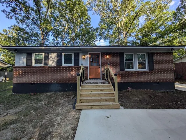 a view of a house with a yard plants and large tree