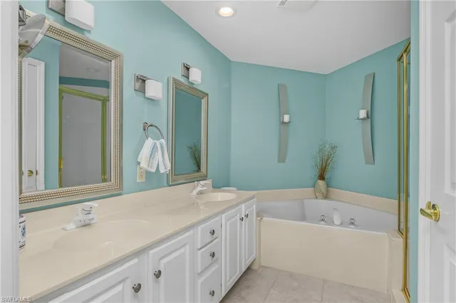 a bathroom with a bathtub double vanity sink and mirror