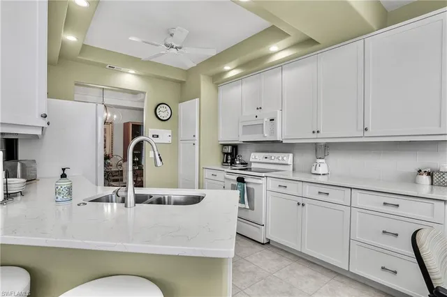 a kitchen with stainless steel appliances kitchen island granite countertop a sink and white cabinets