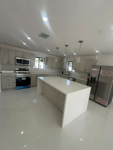 a large white kitchen with a stove a sink a microwave and a refrigerator