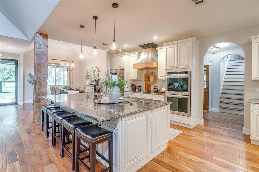 4962 Farm To Market 113 Millsap, TX 76066 - Photo 14 of 36 a kitchen with stainless steel appliances kitchen island granite countertop a table chairs and a wooden floor