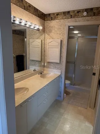 a bathroom with a double vanity sink mirror and shower