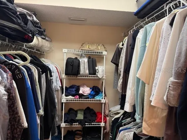 a view of walk in closet with clothes and shoes