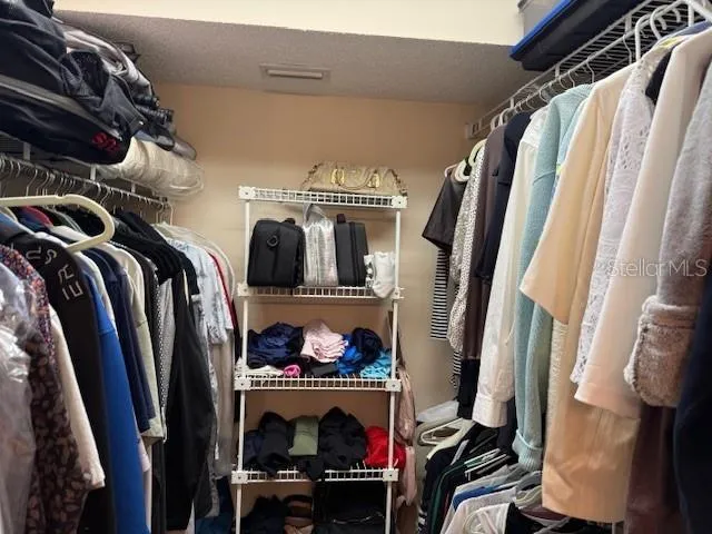 a view of walk in closet with clothes and shoes