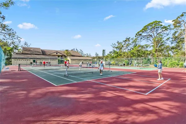 a view of a tennis ground with large trees