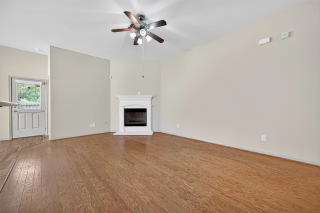 an empty room with chandelier fan and windows