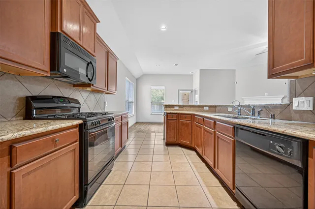 a large kitchen with stainless steel appliances granite countertop a stove top oven a sink dishwasher and cabinets
