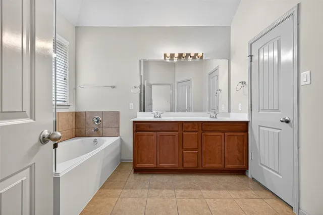 a spacious bathroom with a tub sink and mirror
