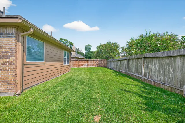 a view of a backyard with plants and wooden fence