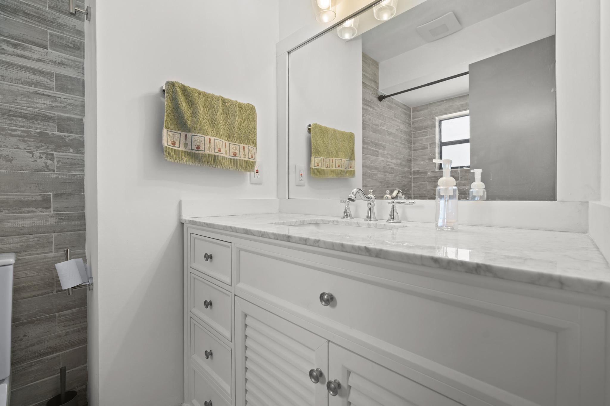 149 Northwest 70th Street, Unit 214C Boca Raton, FL 33487 - Photo 25 of 35 a bathroom with a granite countertop sink a mirror and vanity