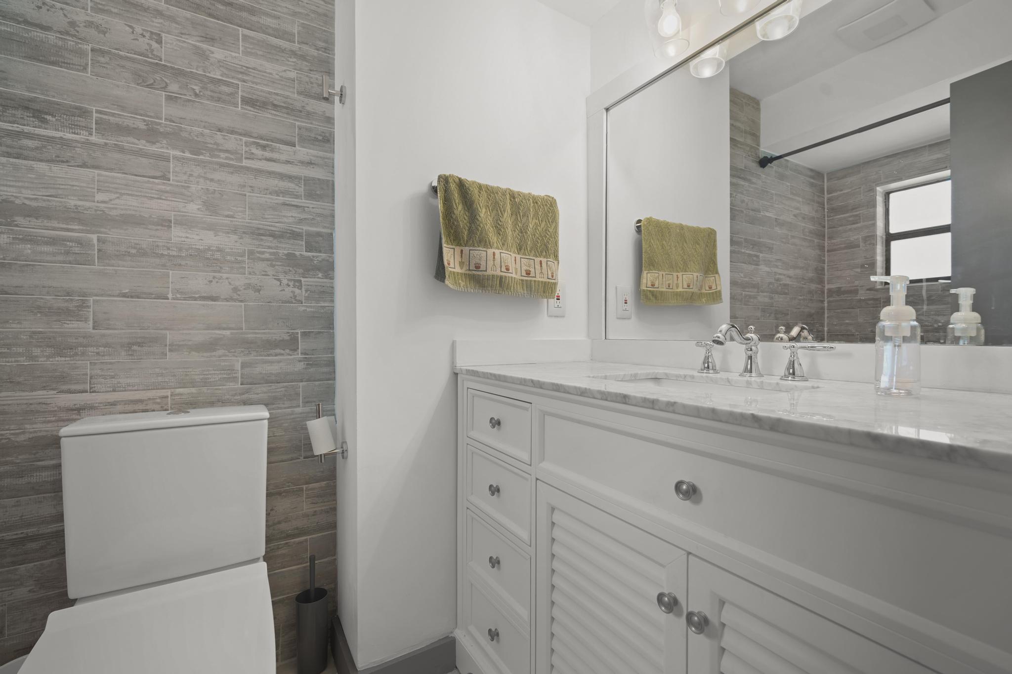 149 Northwest 70th Street, Unit 214C Boca Raton, FL 33487 - Photo 27 of 35 a bathroom with a granite countertop toilet sink and mirror