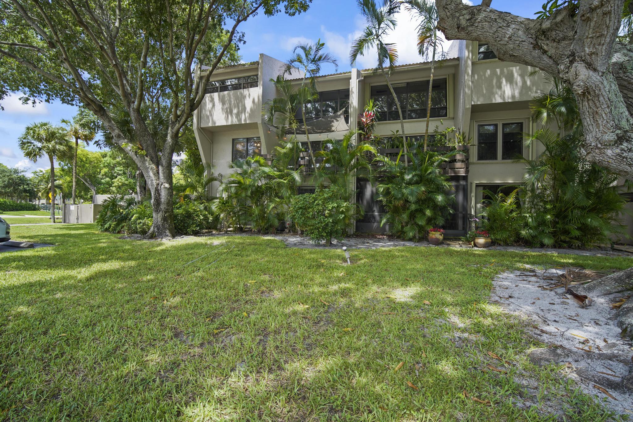 149 Northwest 70th Street, Unit 214C Boca Raton, FL 33487 - Photo 32 of 35 a view of a house next to a big yard and large trees