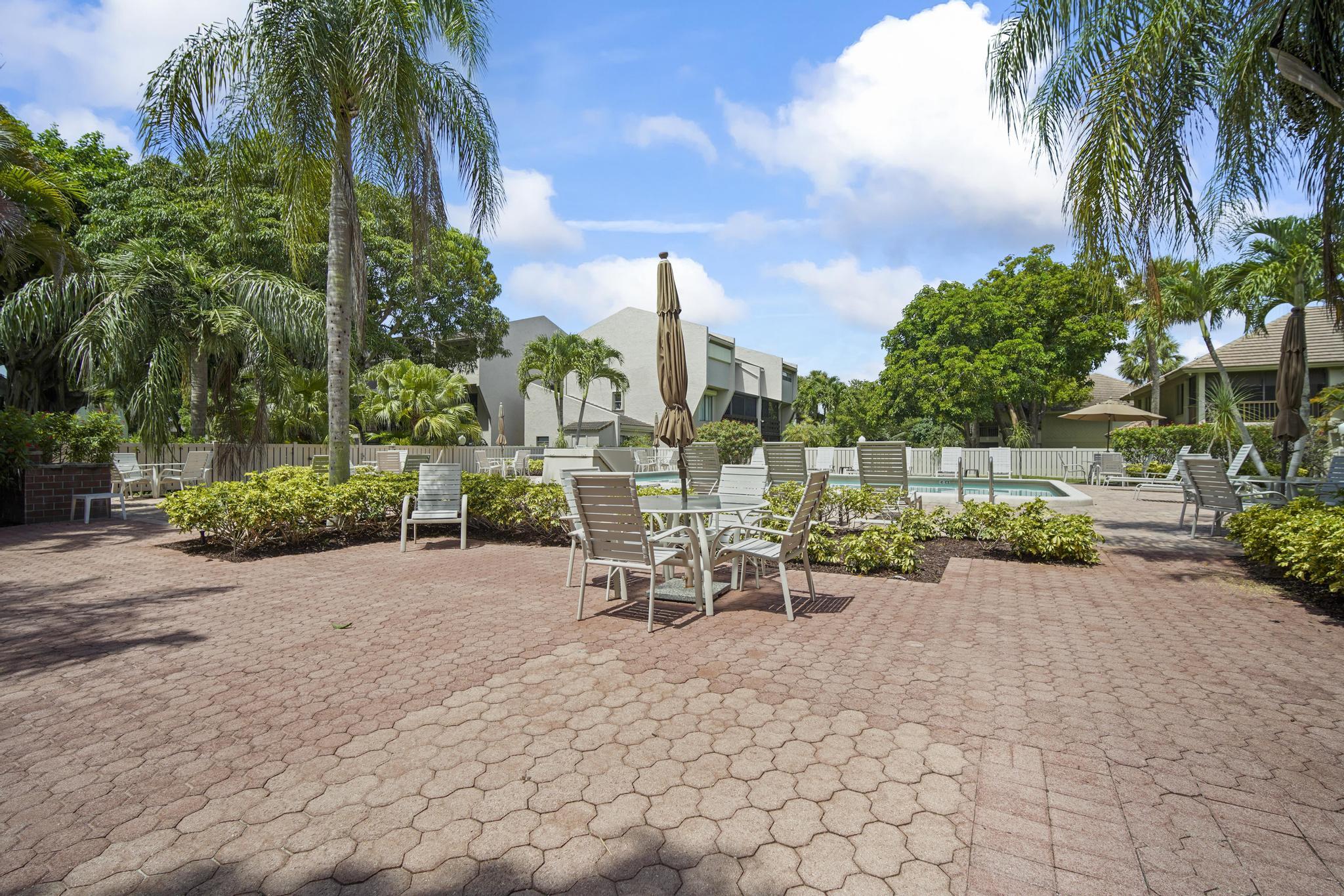 149 Northwest 70th Street, Unit 214C Boca Raton, FL 33487 - Photo 33 of 35 a view of a patio with a table and chairs and potted plants