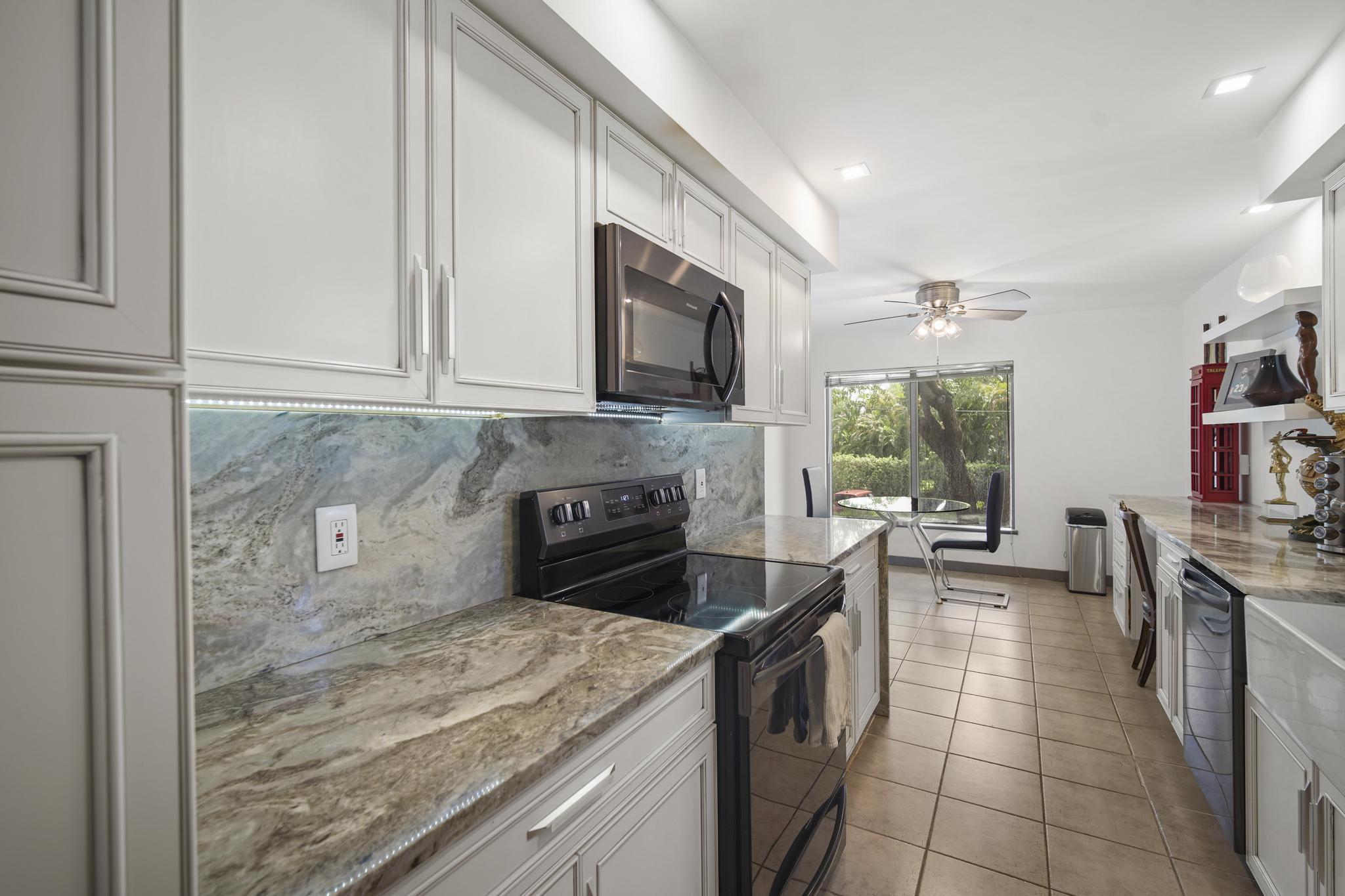 149 Northwest 70th Street, Unit 214C Boca Raton, FL 33487 - Photo 6 of 35 a kitchen with stainless steel appliances granite countertop a stove a sink and a microwave