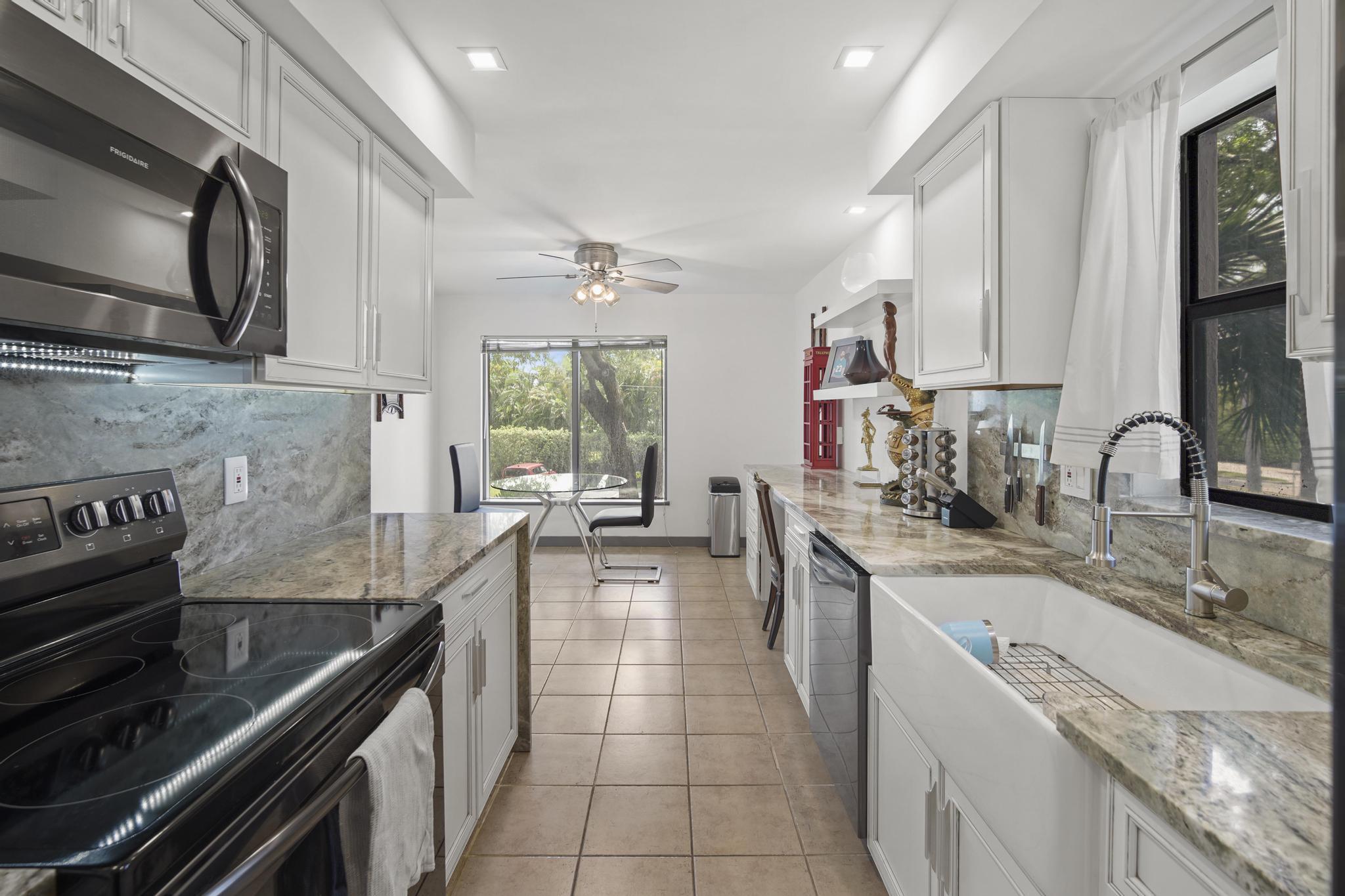 149 Northwest 70th Street, Unit 214C Boca Raton, FL 33487 - Photo 7 of 35 a kitchen with stainless steel appliances granite countertop a sink stove and cabinets
