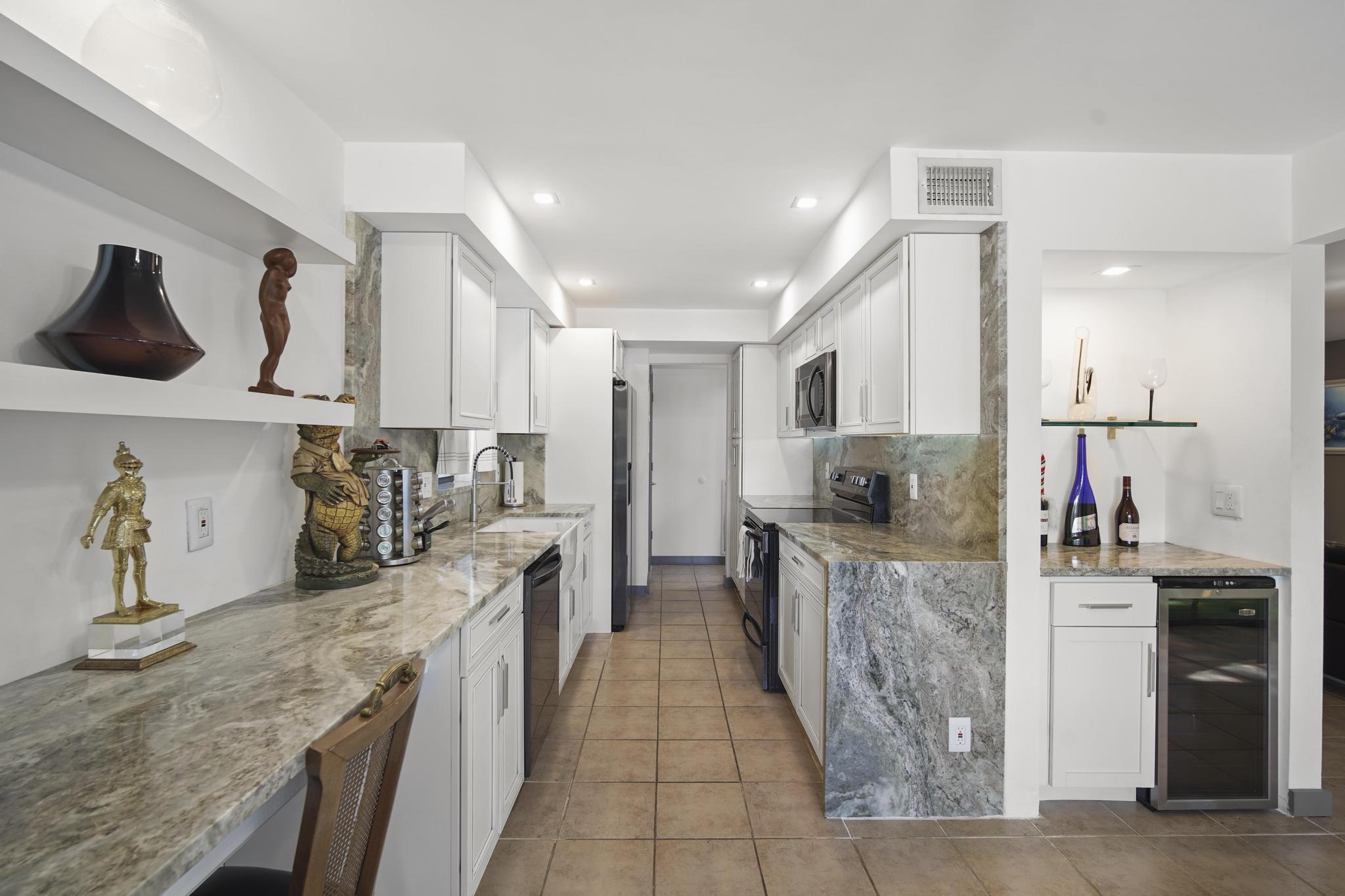 149 Northwest 70th Street, Unit 214C Boca Raton, FL 33487 - Photo 8 of 35 a large kitchen with stainless steel appliances kitchen island granite countertop a sink and cabinets